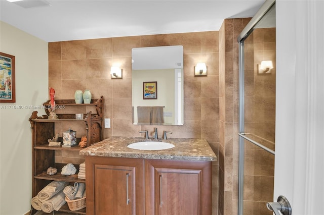 bathroom featuring tasteful backsplash, vanity, a shower with shower door, and tile walls