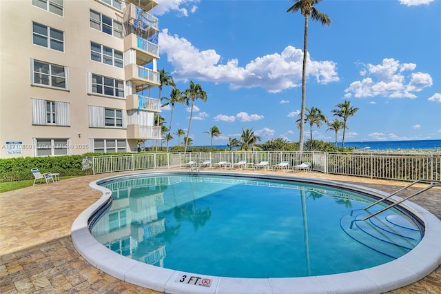 view of pool featuring a water view and a patio