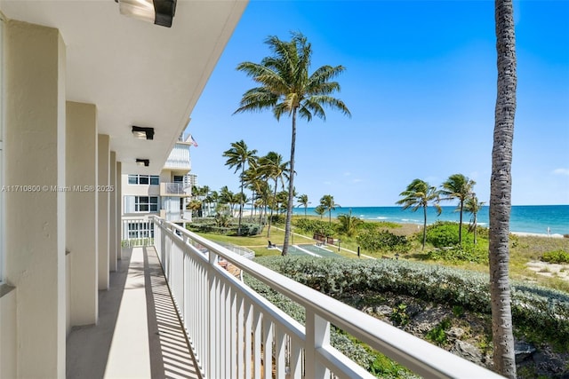 balcony with a water view and a view of the beach