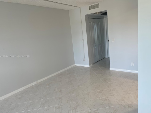 empty room with a textured ceiling and light tile patterned flooring