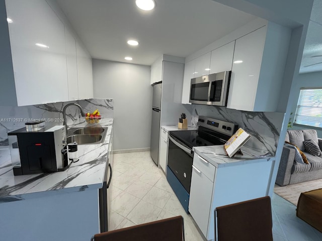 kitchen with stainless steel appliances, white cabinetry, tasteful backsplash, and sink