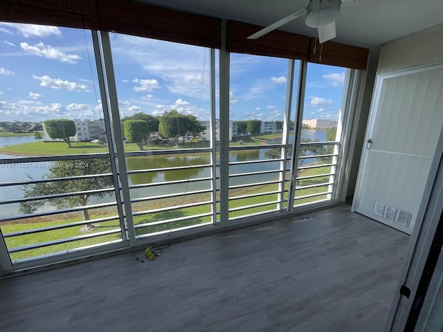 unfurnished sunroom featuring ceiling fan and a water view