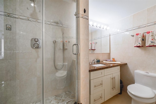 bathroom with vanity, toilet, an enclosed shower, and tile walls