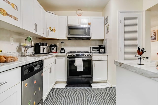 kitchen featuring light stone countertops, appliances with stainless steel finishes, light tile patterned floors, and white cabinetry