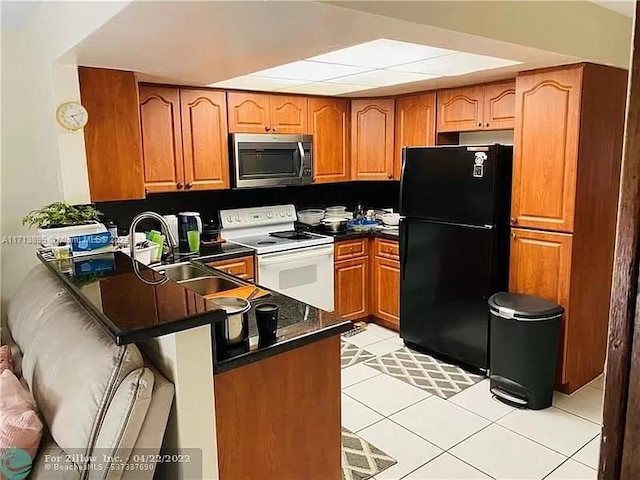 kitchen with electric range, sink, kitchen peninsula, black refrigerator, and light tile patterned floors