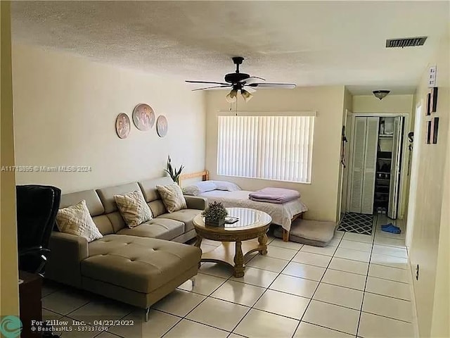 living room featuring ceiling fan, light tile patterned floors, and a textured ceiling