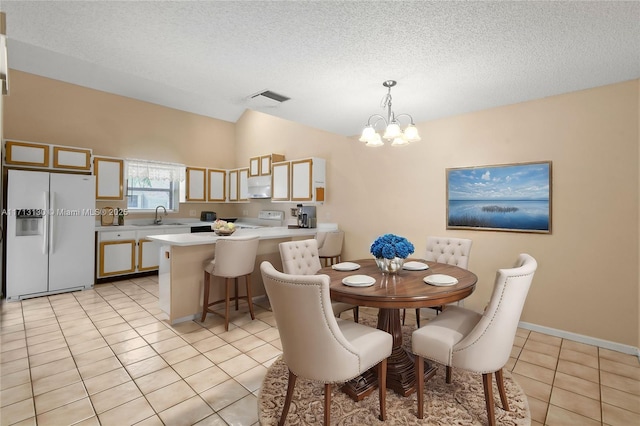 dining room featuring sink, an inviting chandelier, a textured ceiling, light tile patterned flooring, and vaulted ceiling