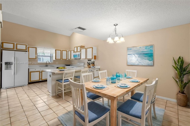 dining room featuring sink, a chandelier, vaulted ceiling, a textured ceiling, and light tile patterned floors