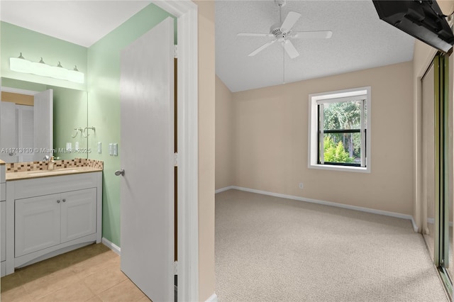 bathroom with ceiling fan, vanity, and a textured ceiling