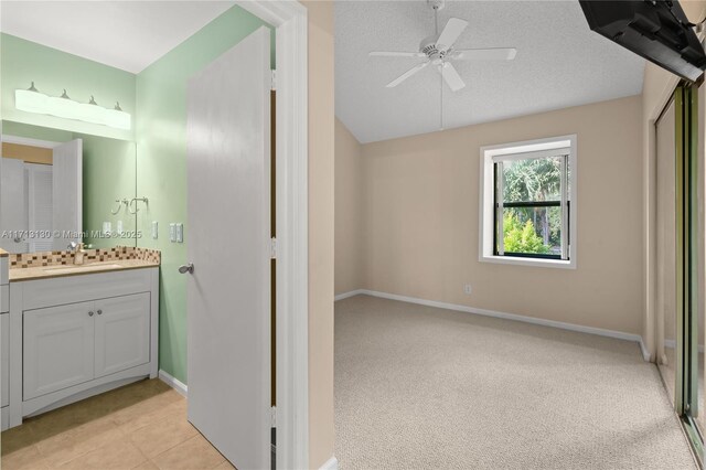 clothes washing area featuring a textured ceiling, washer and clothes dryer, light tile patterned flooring, and sink