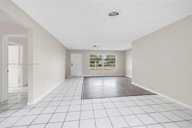 spare room featuring light tile patterned floors and a textured ceiling