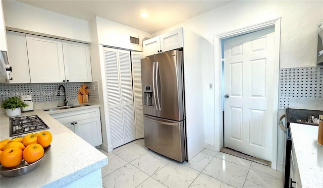 kitchen featuring white cabinetry, sink, decorative backsplash, and stainless steel appliances