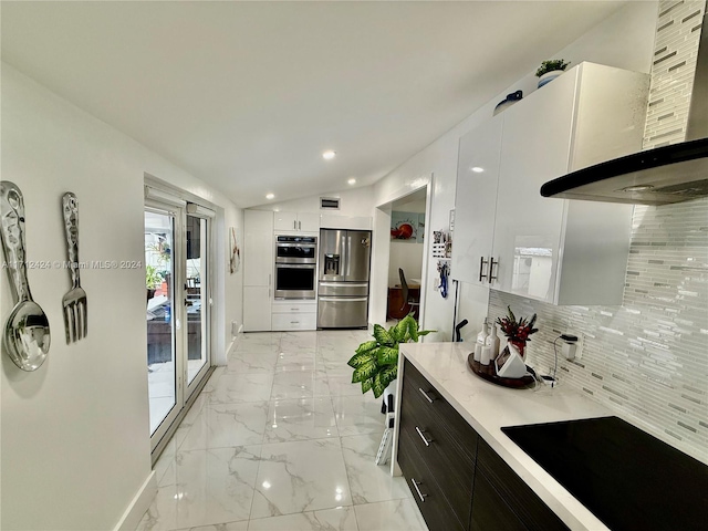 kitchen with appliances with stainless steel finishes, backsplash, vaulted ceiling, extractor fan, and white cabinets