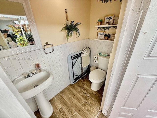 bathroom featuring heating unit, toilet, and tile walls