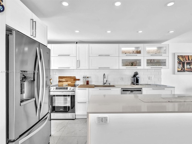 kitchen with decorative backsplash, appliances with stainless steel finishes, light stone counters, sink, and white cabinets