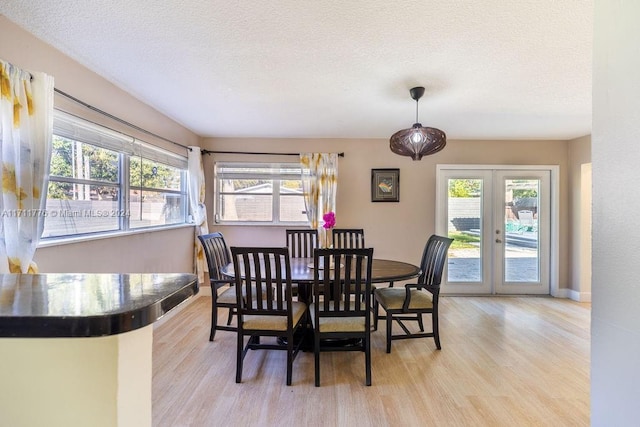 dining area with french doors, a textured ceiling, and a healthy amount of sunlight