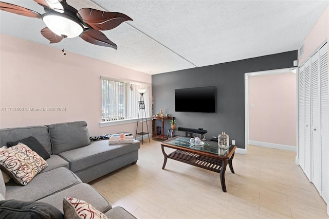 living room with ceiling fan, light hardwood / wood-style floors, and a textured ceiling