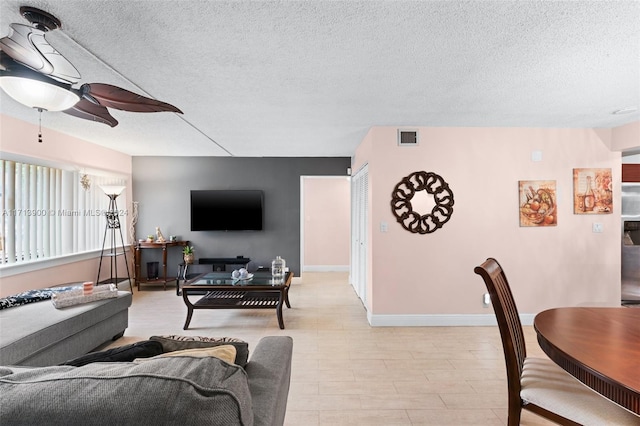 living room featuring ceiling fan and a textured ceiling