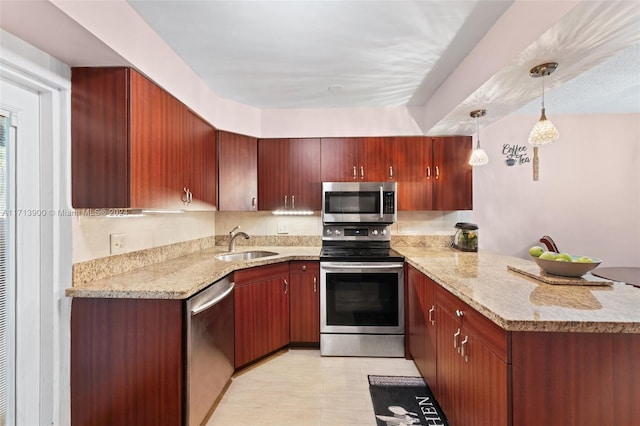 kitchen featuring pendant lighting, sink, appliances with stainless steel finishes, light stone counters, and kitchen peninsula