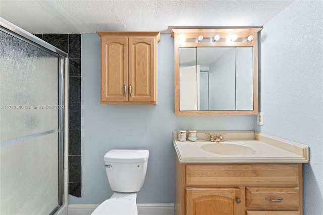 bathroom with vanity, a textured ceiling, toilet, and a shower with door