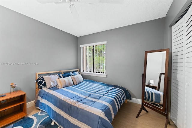 bedroom featuring hardwood / wood-style floors, ceiling fan, a textured ceiling, and a closet