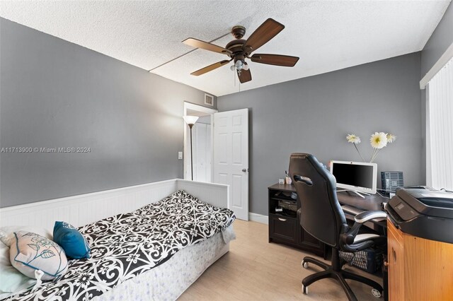 bedroom featuring ceiling fan, light hardwood / wood-style flooring, and a textured ceiling