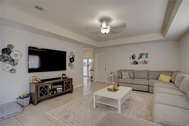 tiled living room featuring a tray ceiling and ceiling fan