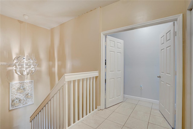 hall with light tile patterned flooring and an inviting chandelier