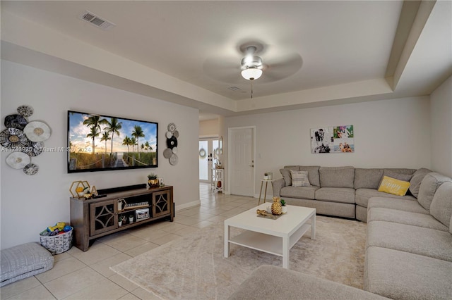 tiled living room featuring a raised ceiling and ceiling fan