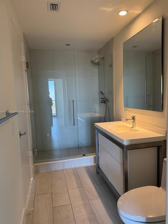 bathroom featuring tile patterned floors, vanity, toilet, and a shower with shower door