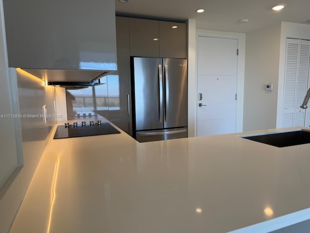 kitchen featuring stainless steel refrigerator, gray cabinetry, sink, extractor fan, and black electric stovetop