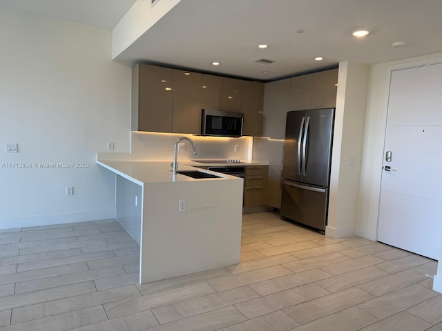 kitchen featuring kitchen peninsula, appliances with stainless steel finishes, gray cabinets, and sink