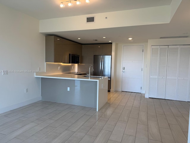 kitchen featuring kitchen peninsula, stainless steel fridge, a kitchen bar, decorative backsplash, and gray cabinetry