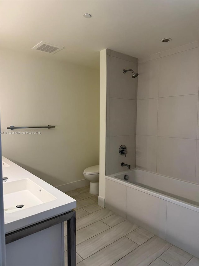 full bathroom featuring toilet, vanity, and tiled shower / bath