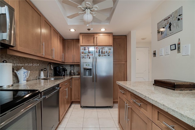 kitchen with decorative backsplash, light stone counters, stainless steel appliances, sink, and light tile patterned flooring