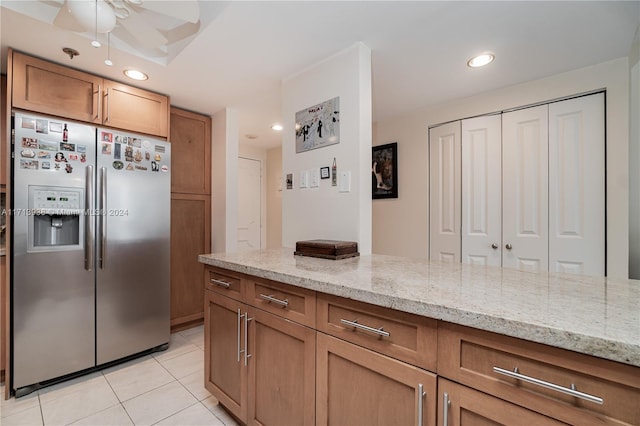 kitchen featuring light stone countertops, stainless steel refrigerator with ice dispenser, light tile patterned floors, and ceiling fan