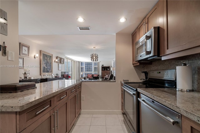 kitchen with kitchen peninsula, appliances with stainless steel finishes, backsplash, and light tile patterned flooring