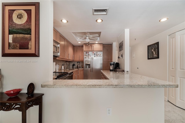 kitchen featuring ceiling fan, kitchen peninsula, stainless steel appliances, and tasteful backsplash