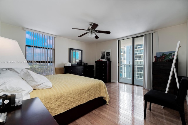 bedroom with hardwood / wood-style floors, ceiling fan, a wall of windows, and access to outside