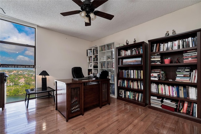 home office featuring ceiling fan, light hardwood / wood-style flooring, and a textured ceiling