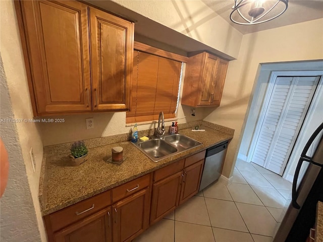 kitchen with sink, light tile patterned flooring, fridge, stone countertops, and stainless steel dishwasher