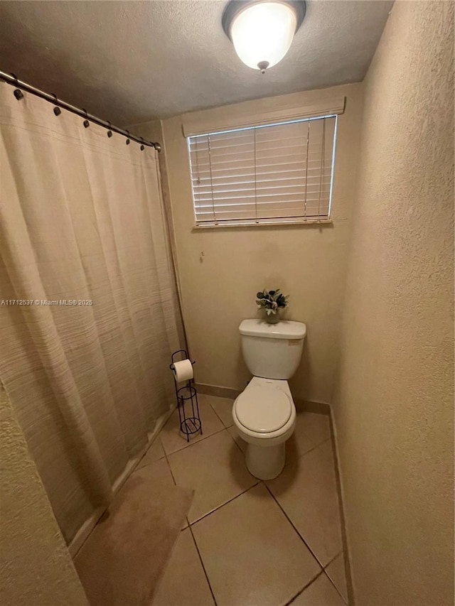 bathroom with tile patterned floors, a textured ceiling, and toilet