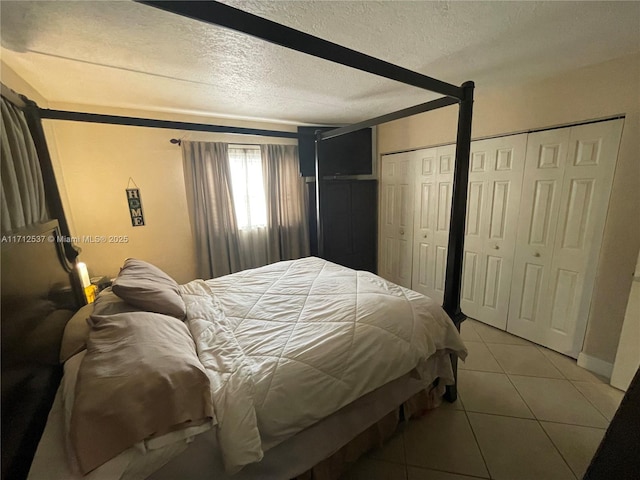 bedroom with tile patterned flooring, two closets, and a textured ceiling