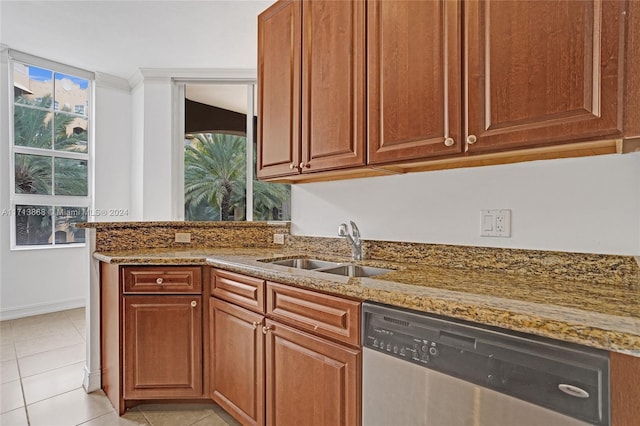 kitchen with stainless steel dishwasher, light tile patterned flooring, light stone countertops, and sink