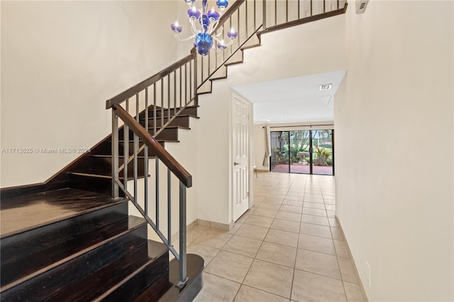 staircase with tile patterned floors and a notable chandelier