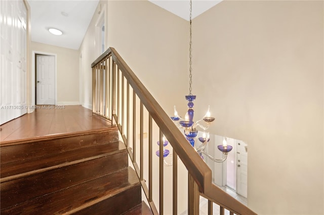 staircase featuring wood-type flooring and an inviting chandelier