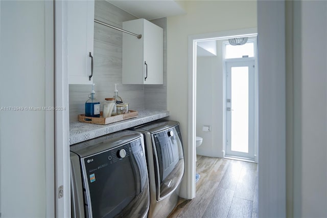 washroom with washing machine and dryer and light hardwood / wood-style flooring