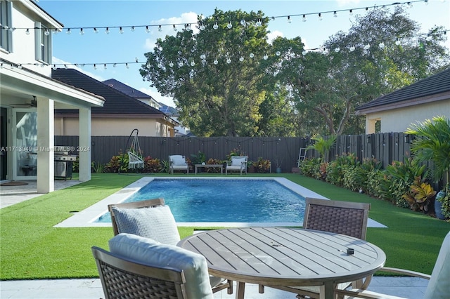 view of pool with a grill, a patio area, and a yard