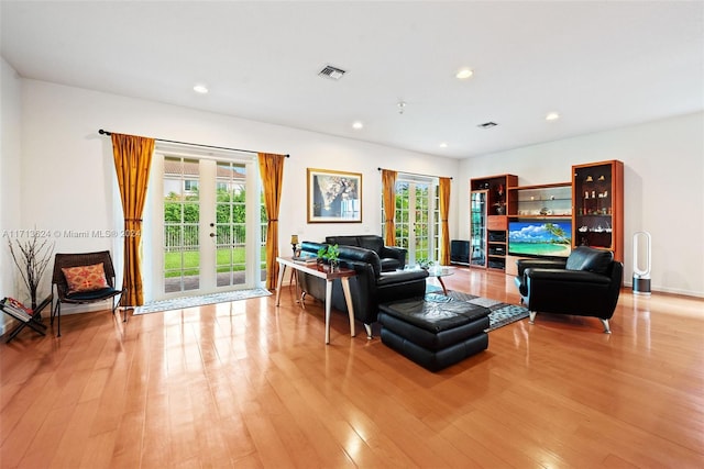 living room featuring light wood-type flooring, a wealth of natural light, and french doors