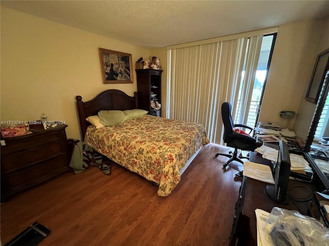 bedroom with a textured ceiling and dark hardwood / wood-style floors